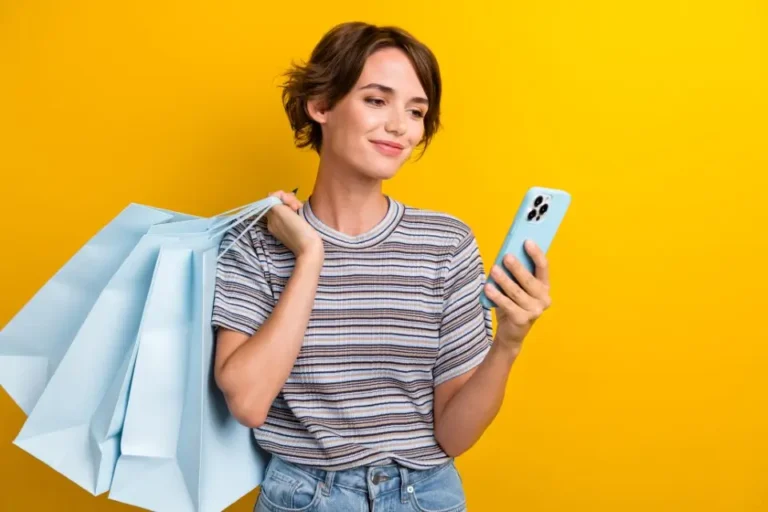 Black Week. Pessoa segurando um celular e bolsas com compras.