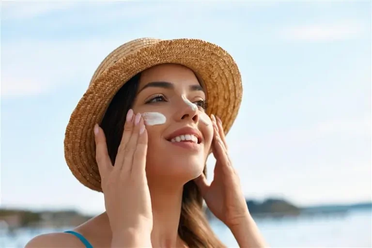 benefícios do protetor solar. Mulher usando chapéu passando protetor solar.